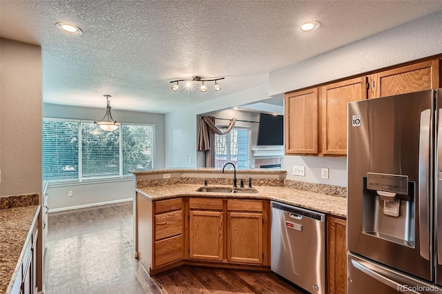 13155 W 63rd Pl, Arvada, CO 80004 - kitchen featuring stainless steel appliances, a peninsula, dark wood-type flooring, brown cabinetry, and a textured ceiling