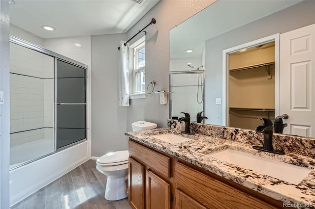 13155 W 63rd Pl, Arvada, CO 80004 - bathroom featuring enclosed tub / shower combo, double vanity, a spacious closet, wood finished floors, and recessed lighting