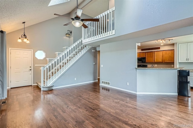 13155 W 63rd Pl, Arvada, CO 80004 - unfurnished living room with stairway, high vaulted ceiling, ceiling fan, wood finished floors, and a chandelier