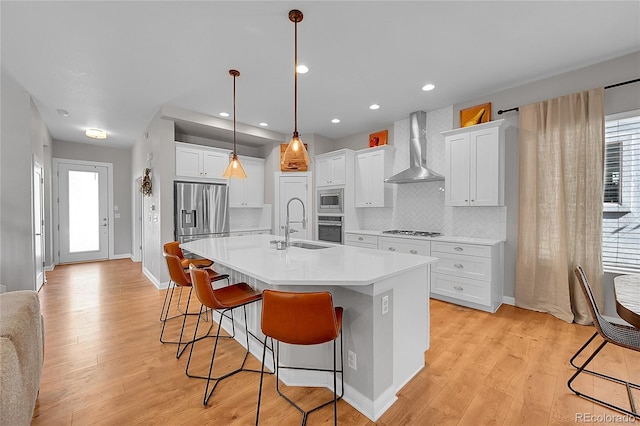 6632 Osage St, Denver, CO 80221 - kitchen with wall chimney range hood, appliances with stainless steel finishes, a sink, a breakfast bar area, and decorative backsplash