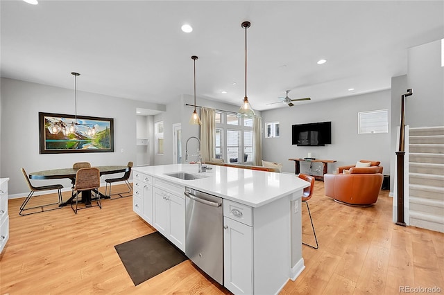 6632 Osage St, Denver, CO 80221 - kitchen featuring stainless steel dishwasher, a sink, light wood finished floors, white cabinets, and light countertops