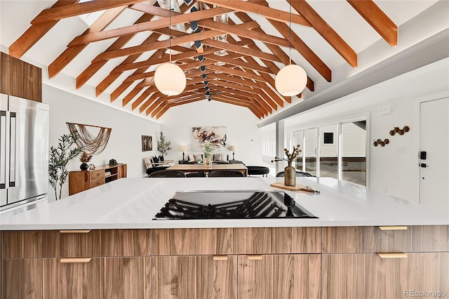 kitchen with modern cabinets, black stovetop, light countertops, and freestanding refrigerator