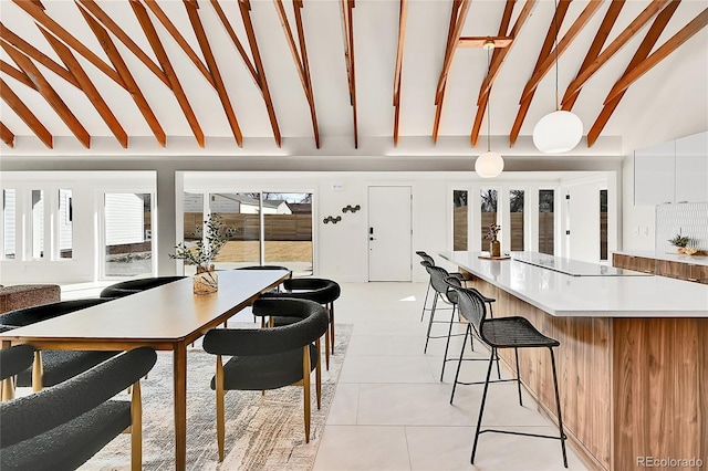 dining area featuring light tile patterned floors and lofted ceiling with beams