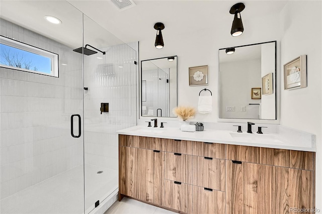 bathroom featuring a shower stall, double vanity, visible vents, and a sink