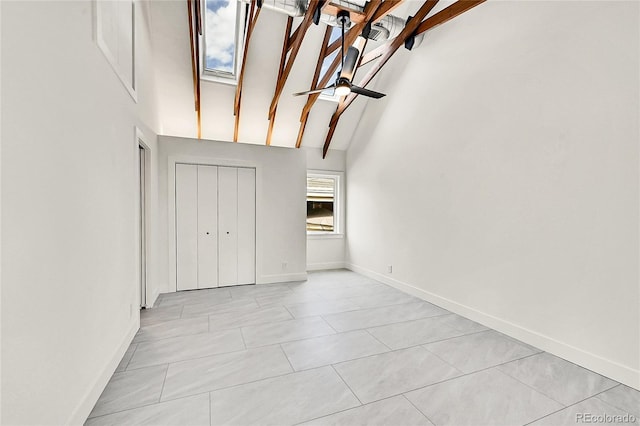 unfurnished bedroom featuring baseboards, high vaulted ceiling, beam ceiling, and a skylight