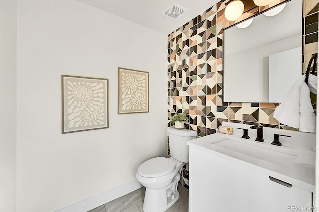 bathroom with visible vents, toilet, vanity, decorative backsplash, and tile walls