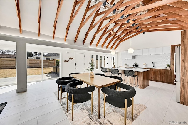 dining area featuring beam ceiling, light tile patterned floors, and high vaulted ceiling