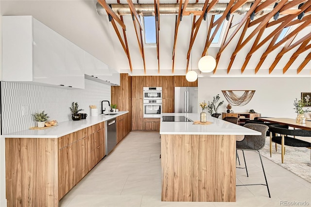 kitchen featuring modern cabinets, a sink, a kitchen island, appliances with stainless steel finishes, and a breakfast bar area