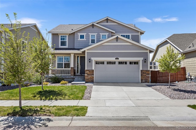 craftsman inspired home with a porch, driveway, fence, an attached garage, and stone siding