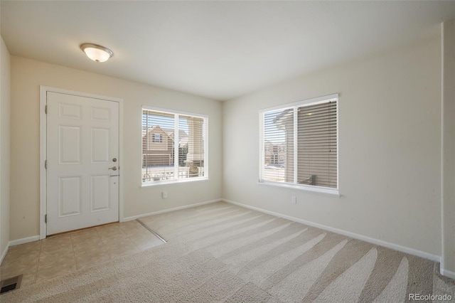 carpeted entrance foyer featuring baseboards, stairs, visible vents, and tile patterned floors