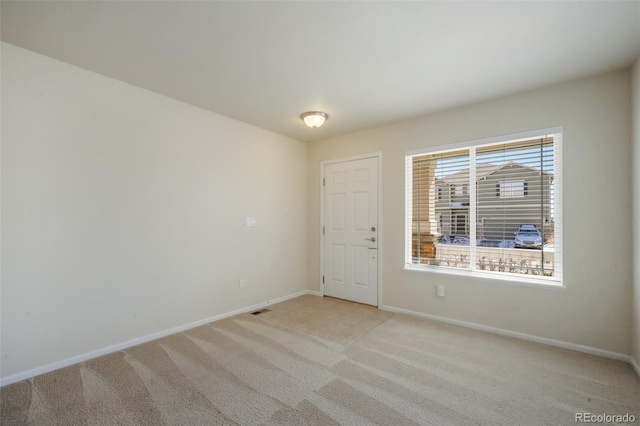 spare room with light colored carpet, visible vents, and baseboards