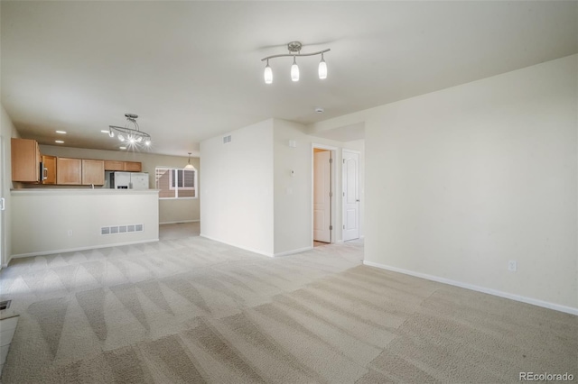 unfurnished living room with baseboards, visible vents, and light colored carpet