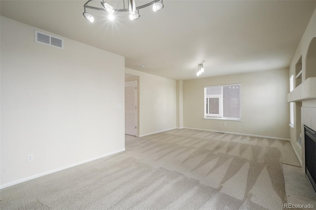 unfurnished living room featuring light carpet, a tiled fireplace, visible vents, and baseboards