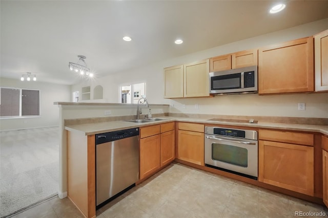 kitchen with appliances with stainless steel finishes, a peninsula, light countertops, a sink, and recessed lighting