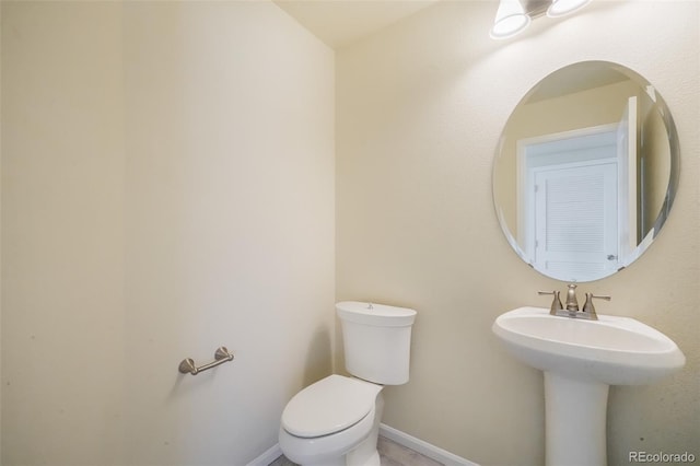 half bathroom featuring toilet and baseboards