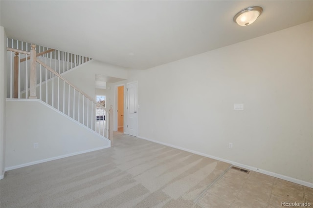 carpeted spare room featuring visible vents, baseboards, and stairs