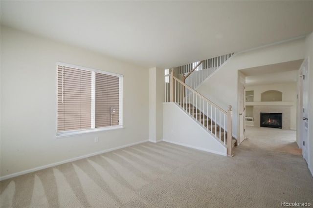 interior space featuring stairs, baseboards, and a glass covered fireplace