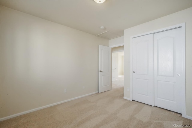 unfurnished bedroom featuring attic access, a closet, light colored carpet, and baseboards