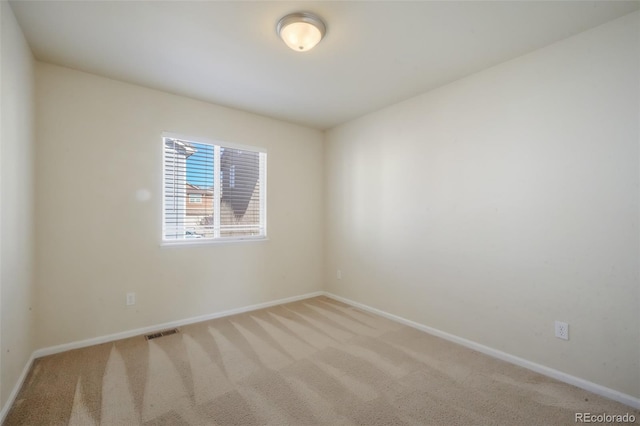 carpeted spare room featuring visible vents and baseboards