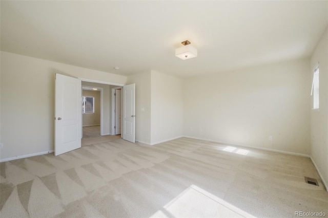 unfurnished room featuring baseboards, visible vents, and light colored carpet