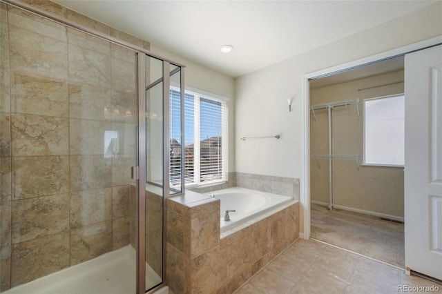 bathroom featuring a spacious closet, a garden tub, a shower stall, and tile patterned floors