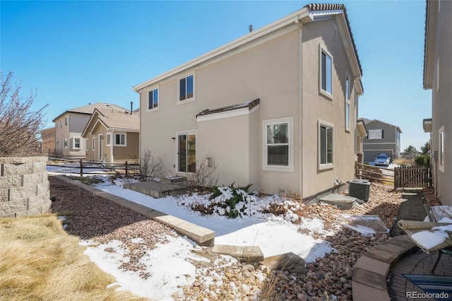 rear view of house with fence and stucco siding