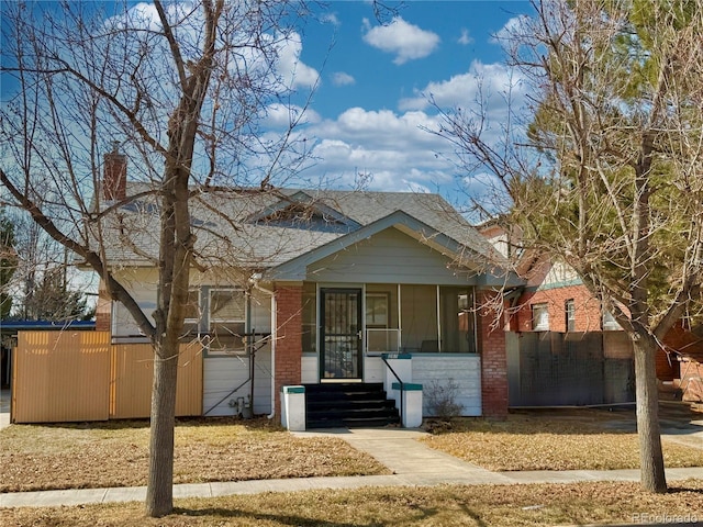 bungalow-style home featuring brick siding and a sunroom