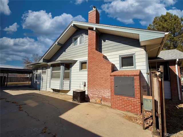 back of house with central air condition unit and a chimney