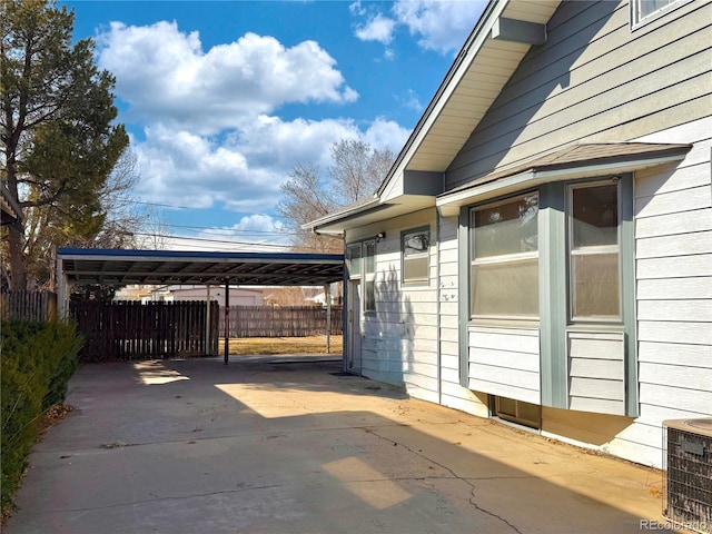 view of patio / terrace featuring a carport, central AC unit, driveway, and fence