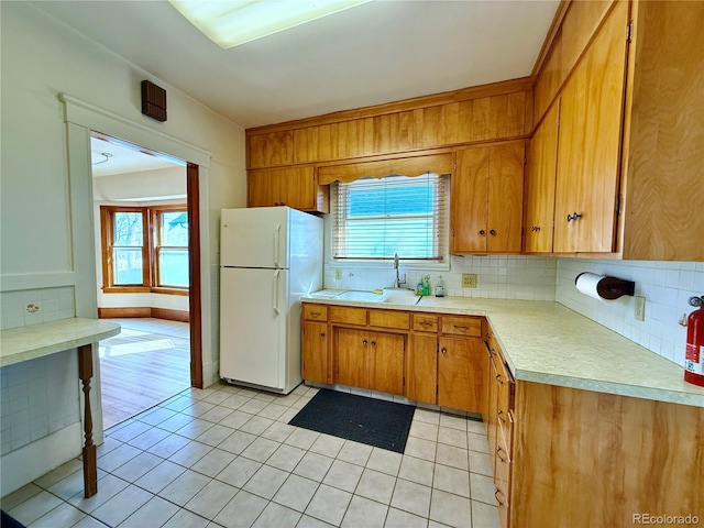 kitchen with a sink, plenty of natural light, light countertops, and freestanding refrigerator