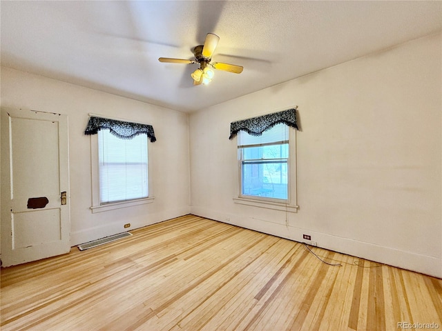 spare room with hardwood / wood-style floors, visible vents, and ceiling fan