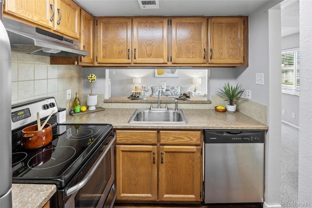 1250 S Monaco Pkwy Unit 50, Denver, CO 80224 - kitchen with stainless steel appliances, under cabinet range hood, light countertops, backsplash, and brown cabinets