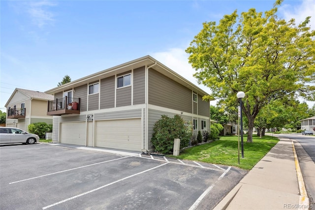 1250 S Monaco Pkwy Unit 50, Denver, CO 80224 - view of side of property featuring a lawn, an attached garage, and uncovered parking