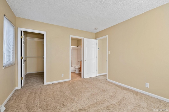 1195 S Oneida St Unit E, Denver, CO 80224 - unfurnished bedroom with carpet, a spacious closet, a textured ceiling, and ensuite bath