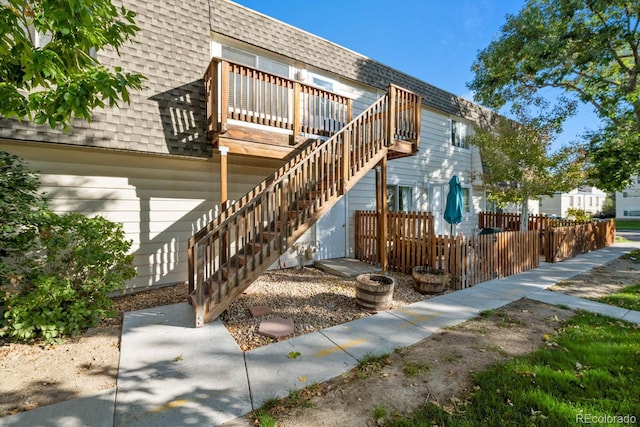 1195 S Oneida St Unit E, Denver, CO 80224 - view of front facade featuring roof with shingles, a deck, and stairs