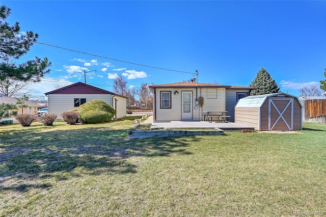 back of property with an outbuilding, a lawn, a shed, fence, and a patio area