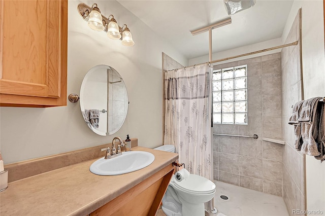 bathroom with a tile shower, toilet, and vanity