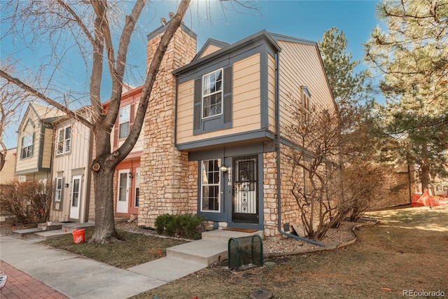 view of front of house with stone siding and a chimney