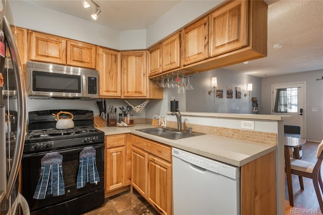 kitchen featuring a peninsula, light countertops, appliances with stainless steel finishes, and a sink