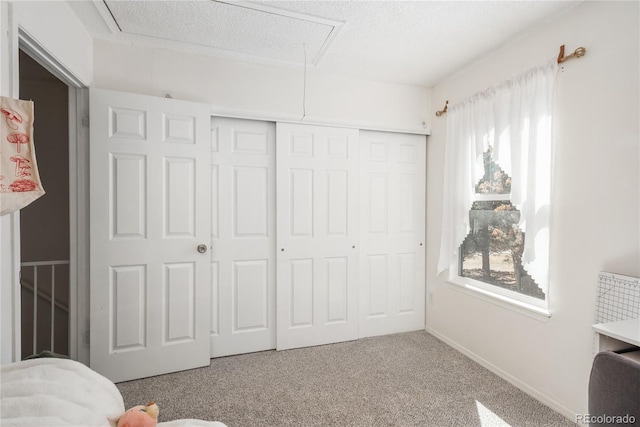 carpeted bedroom with attic access, baseboards, a closet, and a textured ceiling