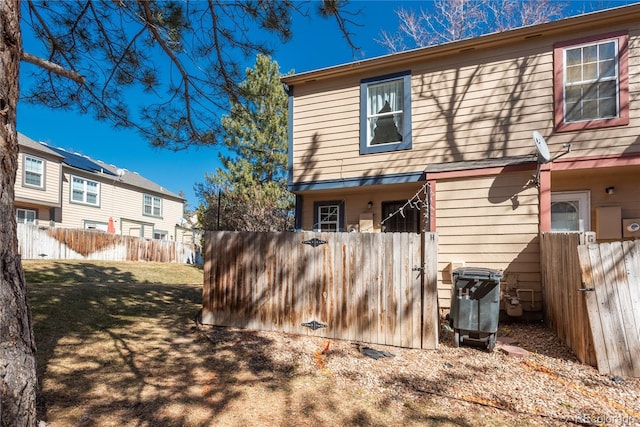 rear view of house featuring a yard and fence