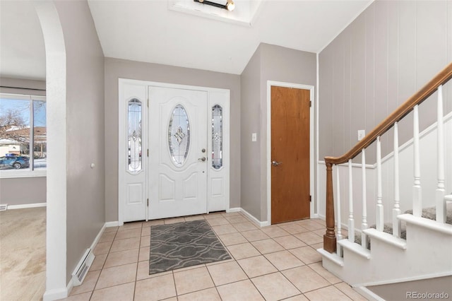 entrance foyer featuring arched walkways, light tile patterned flooring, baseboards, and stairs