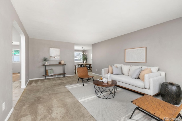 living room with a notable chandelier, carpet, arched walkways, and baseboards