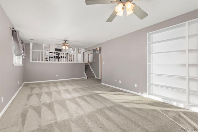 unfurnished living room featuring stairs, carpet floors, a ceiling fan, and baseboards