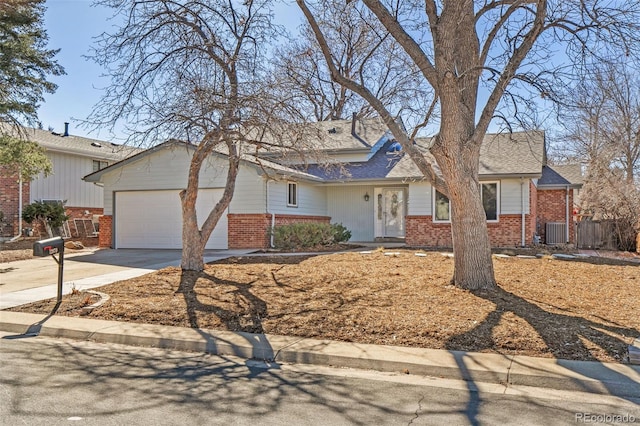 view of front facade with a garage, cooling unit, concrete driveway, and brick siding