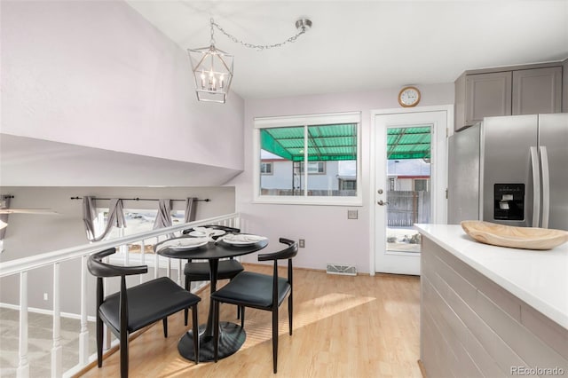 dining space with light wood-style flooring, visible vents, and a notable chandelier