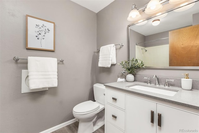 bathroom with baseboards, a shower, toilet, wood finished floors, and vanity