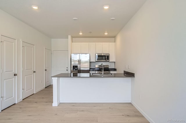 14578 W 90th Ln Unit B, Arvada, CO 80005 - kitchen with stainless steel appliances, a peninsula, light wood-style flooring, dark countertops, and recessed lighting