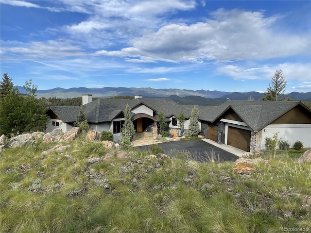 15077 Wilson Peak Rd, Pine, CO 80470 - view of front facade featuring asphalt driveway, a mountain view, an attached garage, a chimney, and a shingled roof