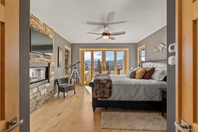 15077 Wilson Peak Rd, Pine, CO 80470 - bedroom with access to outside, hardwood / wood-style flooring, a stone fireplace, and ceiling fan